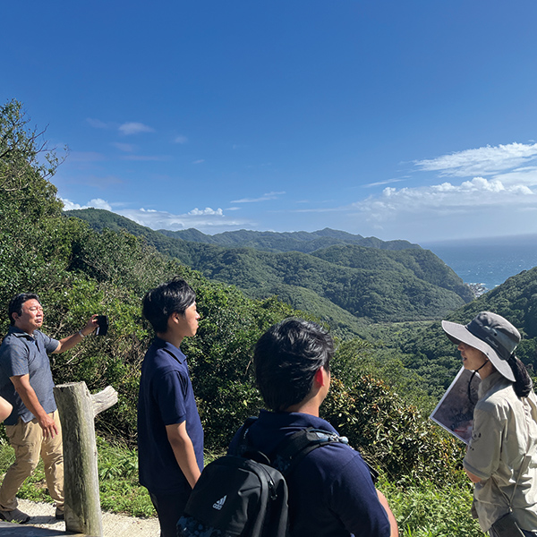 見晴らしの良い山の上で説明を受ける学生たち