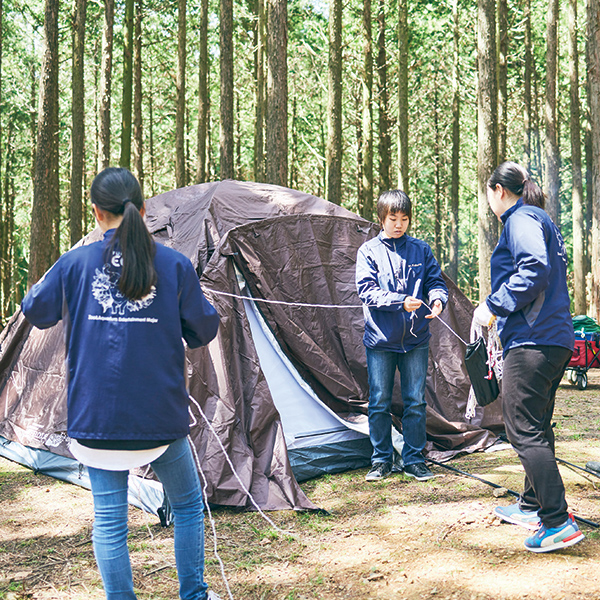 森の中でテントを張る学生たち
